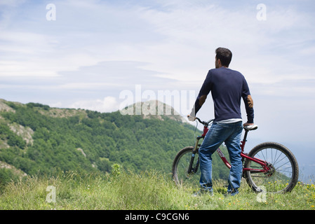 Mann stehend mit dem Mountainbike, malerischen Blick auf die Berge, Sicht nach hinten zu genießen Stockfoto