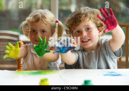 Kleine Mädchen und jungen zeigen Hände bedeckt in Farbe, Porträt Stockfoto