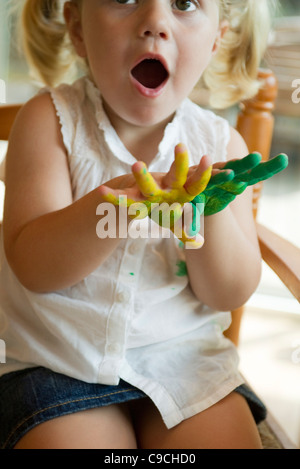 Kleines Mädchen mit Händen bedeckt in Farbe Stockfoto