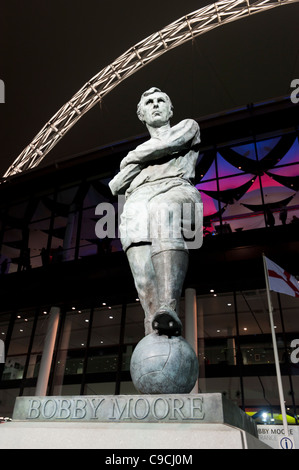 Statue von Bobby Moore vor dem neu entwickelten Wembley Stadion in London, nachts beleuchtet. Stockfoto