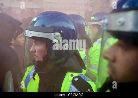 Polizei in Aufruhr Getriebe bildet eine Barriere auf Whitehall, gebadet in roten Rauch aus einem Flare, Studentendemonstration, London, England Stockfoto