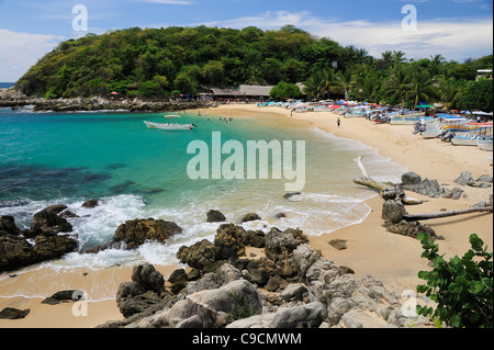 Mexiko, Oaxaca, Puerto Escondido, Blick auf Playa Manzanillo Strand mit Felsen und Touristen Stockfoto