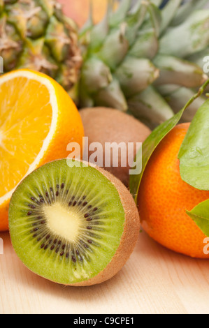 Tropische Früchte - Ananas, Orangen, Mandarinen und Kiwi auf Holztisch Stockfoto