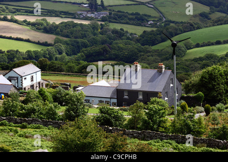 Blick auf grüne Felder und Landschaft, und Hütte mit kleiner Stromerzeugungswindmühle in der Nähe von Minions, Bodmin Moor, Cornwall, England Stockfoto