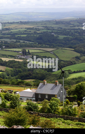 Blick auf grüne Felder und Landschaft, und Hütte mit kleiner Stromerzeugungswindmühle in der Nähe von Minions, Bodmin Moor, Cornwall, England Stockfoto