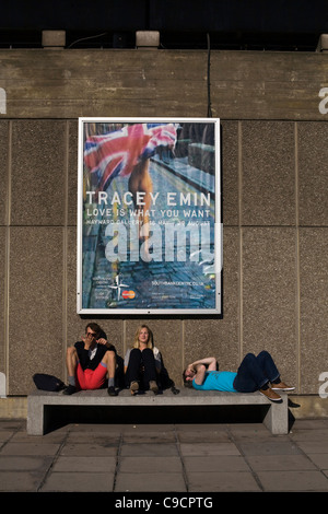 Drei junge Menschen entspannen unter einem Plakat Werbung für eine Show des Künstlers, Tracy Emin von dem National Film Theatre Stockfoto