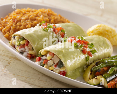 Zwei Gemüse Enchiladas mit cremiger grüner Sauce gekrönt und serviert mit gegrilltem Gemüse und Reis Spanisch Stockfoto