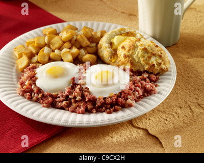 Hash und Ei Frühstück serviert mit Kartoffeln und Kekse und eine Tasse Kaffee Stockfoto