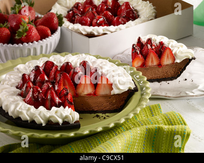 Eine Schokolade Erdbeer Torte mit Sahne und einer Scheibe auf einem weißen Teller und eine to Go-Box im Hintergrund Stockfoto