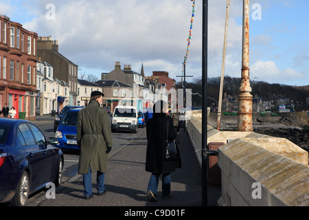 Paar zu Fuß entlang der Uferpromenade Pflaster in Millport auf der Isle of Cumbrae in Ayrshire, Schottland Stockfoto