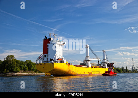 Eine großes Frachtschiff betritt den Hafen eskortiert von Schleppern. Danzig, Polen. Stockfoto