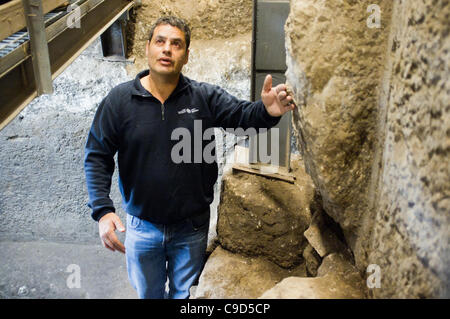 Jerusalem, Israel. 23. November 2011. Ausgrabung Manager Eli Shukron der Israel Antiquities Authority steht in das rituelle Bad, in dem vier antike Münzen gefunden wurden, und verweist auf das Fundament, auf dem die Klagemauer errichtet wurde. Die Münzen bieten Beweis dafür, dass König Herodes nicht die Mauer zu errichten. Stockfoto