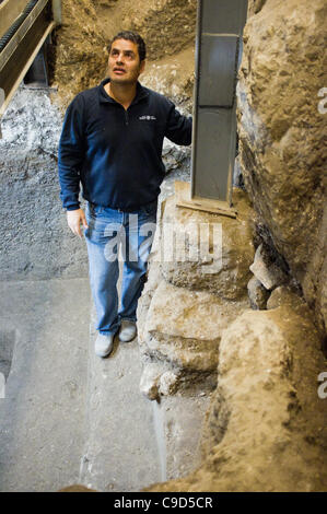 Jerusalem, Israel. 23. November 2011. Ausgrabung Manager Eli Shukron der Israel Antiquities Authority steht in das rituelle Bad, in dem vier antike Münzen gefunden wurden, und verweist auf das Fundament, auf dem die Klagemauer errichtet wurde. Die Münzen bieten Beweis dafür, dass König Herodes nicht die Mauer zu errichten. Stockfoto