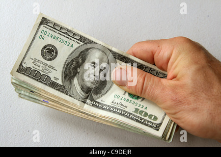 Des Mannes Hand, die Stapel von US-Geld mit 100 Dollar-Schein an der Spitze Stockfoto