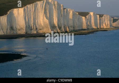 Ein einsamer Fischer steht in der cuckmere Mündung unter den Klippen der Sieben Schwestern in der Nähe von eastbounre, East Sussex, England. Stockfoto