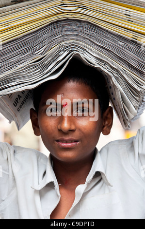 Indischer Zeitungsjunge mit Papieren auf seinem Kopf. Andhra Pradesh, Indien Stockfoto