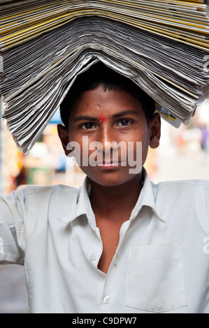 Indischer Zeitungsjunge mit Papieren auf seinem Kopf. Andhra Pradesh, Indien Stockfoto