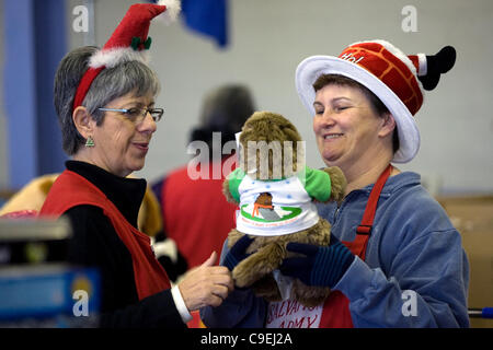 London Ontario, Kanada - 8. Dezember 2011. Cheryl Leyes, links und Kelley Thompson nehmen Sie eine Minute von der Verpackung Weihnachten Geschenkkörbe in den Genuss eine gespendete Spielzeug auf 2011 Heilsarmee Spielzeug und Lebensmittel-Laufwerk Distributionszentrum im Inneren des Gebäudes Fortschritte bei Western Fair District. In diesem Jahr die Salvati Stockfoto