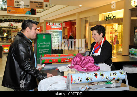 GARDEN CITY, NY, USA - Dezember 09: Merrick Kiwanis Club, ein Community-Service-Gruppe, Geschenk umschließt Urlaub Geschenke um Spenden an Roosevelt Field Shopping Mall auf Freitag, 9. Dezember 2011. Freiwillige Tina Canaris gewickelt Kleider, Shopper, Herr Hernandez, kaufte für neugeborenes Anfang dieser Woche. Stockfoto