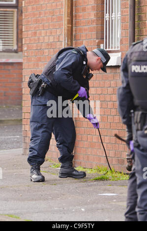 Belfast, UK.  12.12.2011: Polizist von der Polizei sucht Hinweise während der Investigatation in die Dreharbeiten Vorfall außerhalb Kiosk-Shop in Nordbelfast Stockfoto