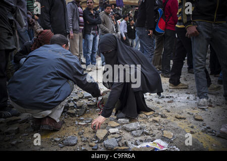 17. Dezember 2011 - Kairo, Ägypten - Demonstranten Scherben aufzusammeln Schutt am zweiten Tag der Kämpfe gegen die Militärpolizei in Midan Tahrir, Innenstadt von Kairo.  Die Zusammenstöße brach aus, als ein kleiner Protest vor das ägyptische Parlament gestern früh angegriffen wurde.  Als ein Ergebnis der ägyptischen Stockfoto