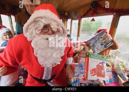 Der Weihnachtsmann und seine Elfen unterhalten und Geschenke für Kinder an Bord der Welsh Highland Railway in Snowdonia North Wales.on 17 Dezember 2011 Stockfoto