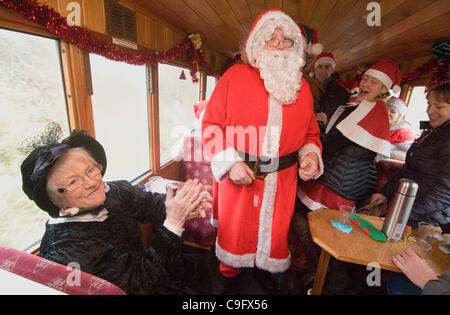 Der Weihnachtsmann und seine Elfen unterhalten und Geschenke für Kinder an Bord der Welsh Highland Railway in Snowdonia North Wales.on 17 Dezember 2011 Stockfoto