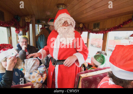 Der Weihnachtsmann und seine Elfen unterhalten und Geschenke für Kinder an Bord der Welsh Highland Railway in Snowdonia North Wales.on 17 Dezember 2011 Stockfoto