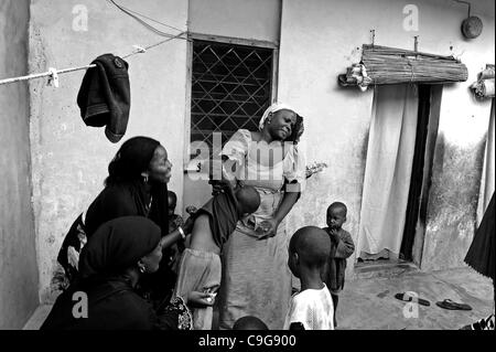 18. September 2010 - Kano, KANO, NIGERIA - überstimmen die Proteste des Rechts, eine Mutter, die den Polio-Impfstoff für ihre Kinder abgelehnt hatte; Josephine Kamara, UNICEF-Beauftragter für soziale Mobilisierung für die Polio-Impfstoff Kampagne, ganz links, in schwarz, impft fünf Kinder gegen Polio. Ein v Stockfoto