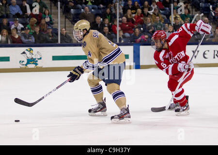 31. Dezember 2011 - South Bend, Indiana, USA - Notre Dame Center prüft Riley Sheahan (#4) Laufwerke mit dem Netz als Boston University Verteidiger Alexx Privitera (#6) zurück in die zweite Periode Aktion des NCAA-Eishockey-Spiel zwischen Notre Dame und der Boston University.  Die Notre Dame Fighting Irish besiegt Boston Stockfoto