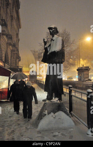 Schnee fällt auf London Samstagabend. Pendler-Kopf durch den Schnee hinter dem Sherlock Holmes-Statue außerhalb Baker Street Station. Stockfoto