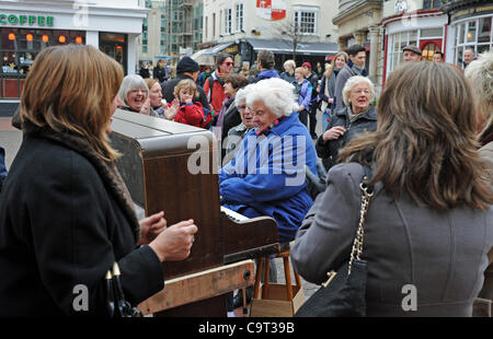 Eine Gruppe von Damen genießen einen spontanes Singen Gesang und Tanz, wie sie ein Straßenmusiker Piano in The Lanes Bereich von Brighton leihen Stockfoto