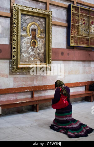 Eine Frau kniet in Gebet, bevor ein Bild von Christus mit Maria als Tausende von christlichen Pilgern und Gläubigen in Scharen Kirche des Heiligen Grabes am Aschermittwoch. Jerusalem, Israel. 22. Februar 2012. Stockfoto