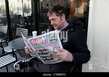 Ein Mann im Bild, lesen die neue Sonne am Sonntagszeitung vor einem Geschäft in Brighton, East Sussex, UK. Stockfoto