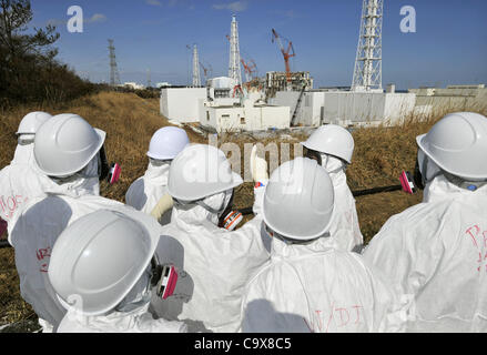 28. Februar 2012 - Okuma, Fukushima, Japan - Mitglied der Medien begleitet von TEPCO-Mitarbeiter, tragen Tyvex Schutzanzüge und Masken-Blick auf die Nummer 3 und Nummer 4 Reaktorgebäude der Tokyo Electric Power Co. (TEPCO) des Tsunami verkrüppelt Fukushima Daiichi Atomkraftwerk in Okuma, Fukushim Stockfoto