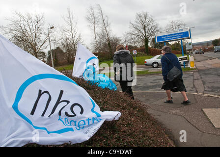 03.07.2012, Exeter, UK. Eine NHS gemeinsam Flagge flattert im Wind Baracke unterwegs, als zwei Frauen vorbei, während der NHS-Reform-Protest vor dem Royal Devon & Exeter Krankenhaus gehen. Stockfoto