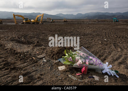 Blumen markieren die stellen, wo Häuser standen und wo Menschen in dem Tsunami 2011 in der schlammigen Ebene, wo einst starben die Gemeinschaft von Kamaya, über 1 Jahr-Jubiläum der 11. März 2011 Erdbeben und Tsunami in Kamaya, Tohoku-Region stand, im Sonntag, 11. März 2012 Japan. Stockfoto