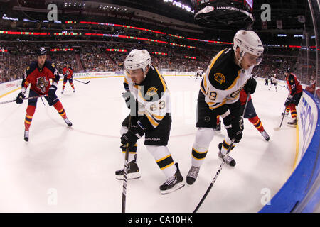 15. März 2012 - Sunrise, Florida, gräbt Vereinigte Staaten von Amerika - Center Boston Bruins Tyler Seguin (19) für den Puck mit Boston Bruins linken Flügel Brad Marchand (63) während der Florida Panthers Verteidiger Erik Gudbranson (44) tritt in der ersten Phase zwischen den Boston Bruins und die Florida Panthers Stockfoto