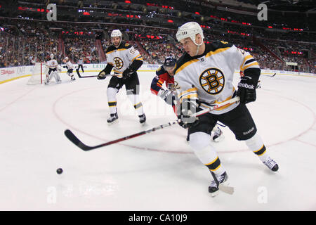 15. März 2012 - Sunrise, Florida, Vereinigte Staaten von Amerika - Boston Bruins rechten Flügel Shawn Thornton (22) Schlittschuhe mit dem Puck mit Florida Panthers Tomas Kopecky (82) dicht Zentrum hinter während Boston Bruins Verteidiger Adam McQuaid (54) in der zweiten Periode zwischen den Boston Bruins blickt auf eine Stockfoto