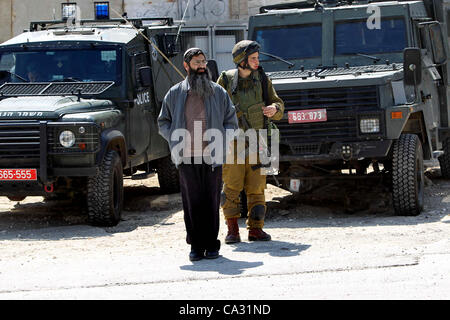 29. März 2012 - Hebron, Westjordanland, Palästinensische Autonomiegebiete - israelische Siedler Spaziergang vorbei an israelischen Grenzpolizisten Wachposten vor einem besetzten palästinensischen Haus nach Dutzenden von jüdischen Siedlern das Anwesen über Nacht übernahm, behaupten sie das rechtliche Eigentum, in der besetzten Westbank-Stadt der Stockfoto