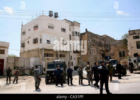 29. März 2012 - Hebron, Westjordanland, Palästinensische Autonomiegebiete - israelische Siedler Spaziergang vorbei an israelischen Grenzpolizisten Wachposten vor einem besetzten palästinensischen Haus nach Dutzenden von jüdischen Siedlern das Anwesen über Nacht übernahm, behaupten sie das rechtliche Eigentum, in der besetzten Westbank-Stadt der Stockfoto