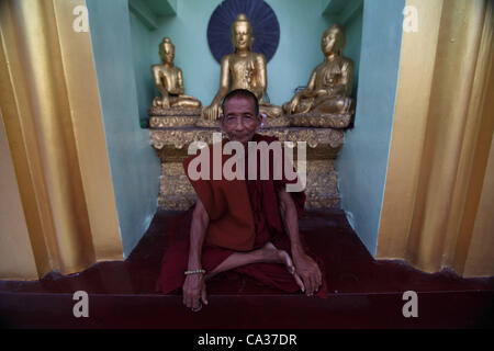 Ein Mönch sitzt vor Buddhastatuen an der Shwedagon-Pagode in Yangon, 30. März 2012.  Eine Welle von Reformen in Politik, Medien und Wirtschaft vor den Wahlen, die Demokratie Symbol Aun San Suu Kyi, Parlament, katapultieren könnte haben löste internationale Interesse im jeweiligen einmal isoliert Mya Stockfoto