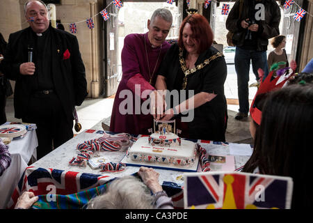 London, Vereinigtes Königreich, 06.02.2012. Der Bürgermeister von Camden, Heather Johnson schneiden das Jubiläum Kuchen mit Peter Wheatley, der Bischof von Edmonton. Der Kuchen wurde rund um die Jubiläums-Partygänger geteilt. Vater David Houlding ist Standiing mit einem Mikrofon Stockfoto