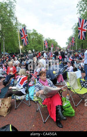 Die Mall, London, UK. 4. Juni 2012. Eine Frau liest das Papier unter den Tausenden The Mall vor dem Start des Diamond Jubilee Konzertes zu füllen. Stockfoto