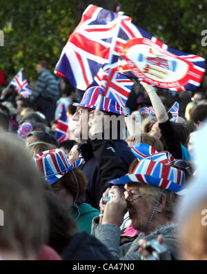 London, UK. 4. Juni 2012. Patriotische Fans genießen das Konzert zur Feier der Königin Diamond Jubilee auf den großen Leinwänden im St. James Park, mit Union Jack-Flaggen und Hüte. Stockfoto