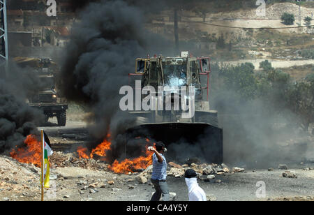 8. Juni 2012 - Nablus, West Bank, Palästina - palästinensische Demonstranten mit Steinen werfen in Richtung israelische militärische Planierraupe bei Auseinandersetzungen nach einer Demonstration gegen die nahe gelegene jüdische Siedlung Kdumim, im Westjordanland-Dorf von Kfar Kadum, in der Nähe von Nablus 8. Juni 2012 (Credit-Bild: © Neda Stockfoto