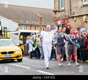 Thomas Tracey, 59, ein Charity-Marathon-Läufer aus Glasgow, winkt der Menschenmenge wie er trägt das Olympische Feuer im Dorf Barrmill in North Ayrshire, Schottland, am 8. Juni 2012. Stockfoto