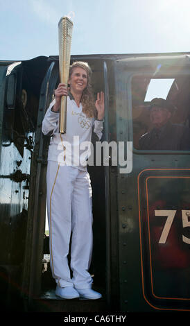 Whitby, Großbritannien. Montag, 18. Juni 2012. Sportlehrer Kelly Williams stellt mit der Olympischen Fackel auf die Fußplatte der Dampfmaschine The Green Knight an Whitby Station. Der Motor wurde in der Sir Nigel Gresley am Bahnhof Grosmont geändert. Stockfoto