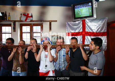 LA PAZ, BOLIVIEN, 24. Juni 2012. Eine Mischung aus englischen Reisenden und Expats, die während des Viertelfinalspiels der UEFA-Fußball-Europameisterschaft zwischen England und Italien (das live im Fernsehen dahinter übertragen wird) in Olivers English Pub in La Paz Trinkspiele spielen. Stockfoto