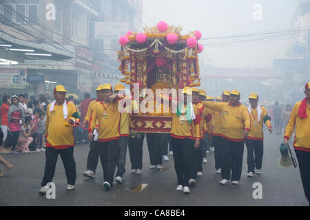 Samut Sakhon Provinz, Thailand, 26. Juni 2012. Men führt Stadt Säule Gott durch den Markt.  Chaopho Lak Mueang Prozession oder The Shrine of City-God-Parade findet im Juni jedes Jahr an der Böschung vor dem Rathaus. "Chaopho Lak Mueang" befindet sich dann in einer Sänfte auf einem Fischerboot, die wunderschön geschmückt mit Fahnen und schwebte am Flussufer Tha Chin von Talat Maha Chai, Tha Chalom im Bereich des Wat Suwannaram und weiter nach Wat Chong Lom, bietet eine Möglichkeit für die Menschen zu achten und zu gewinnen Glück. Stockfoto